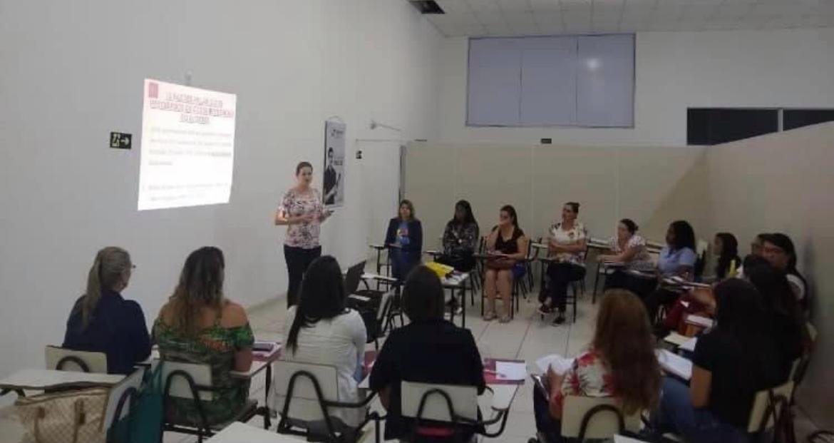 Lorena Lima conduzindo o curso sobre TEA em Lavras, diante da turma.