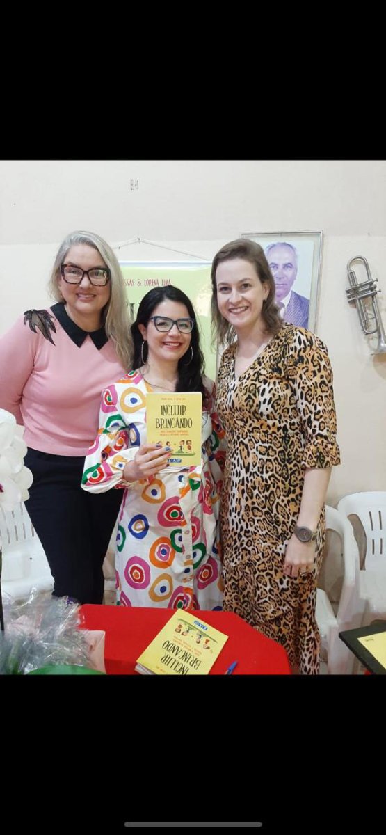 As autoras com uma leitora segurando o livro Incluir Brincando.