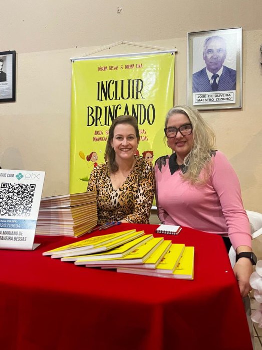 Débora Bessas e Lorena Lima no estande do Incluir Brincando, com exemplares do livro sobre a mesa.