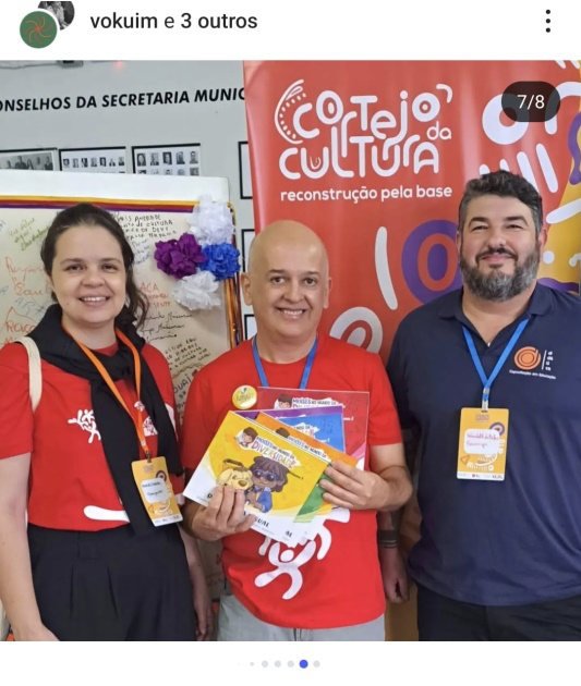 Débora Bessas com dois participantes do Cortejo da Cultura, segurando livros da coleção.