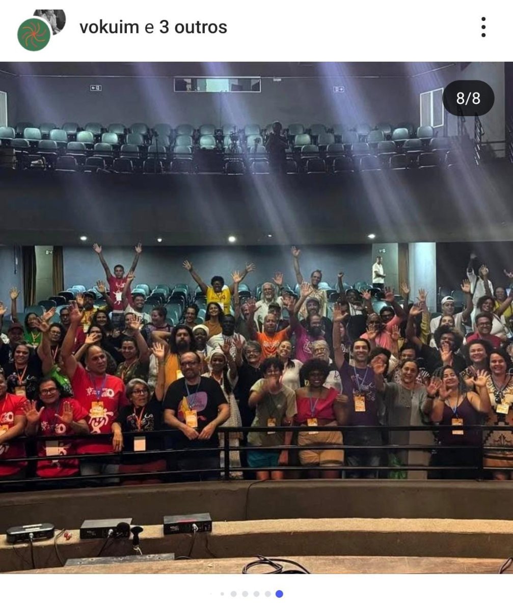 Plateia do Cortejo da Cultura em Itaúna, de braços levantados no auditório.